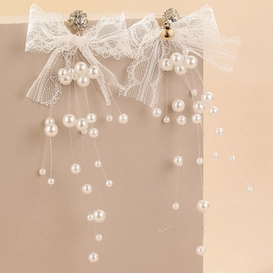 Détail de boucles d'oreilles en dentelle avec strass brillants et franges de perles