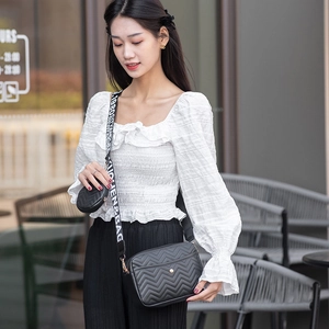 Detail of black V-quilted crossbody bag with wide logo strap and mini coin purse pouch