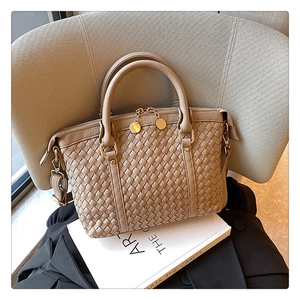 Détail d'un sac à main en cuir tressé beige avec fermeture éclair dorée et pendentif