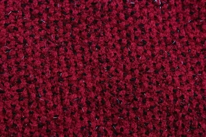 Primer plano de tela tweed roja y negra con fibras metálicas sutiles y flecos