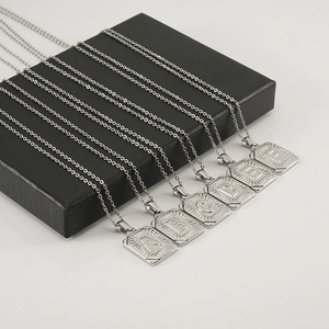 Detail of square stainless steel letter pendants A to F arranged on a black jewelry box