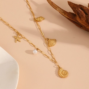 Detailed view of gold starfish, shell, and pearl charms on a rectangle link necklace