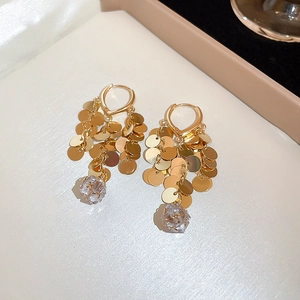 Detail of gold leaf sequin fringe earrings with dangling crystals on a white display