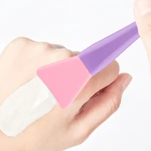 Silicone face mask brush with purple handle applying cream on skin for skincare