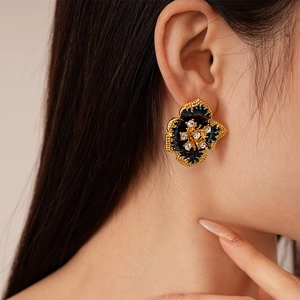 Détail d'une boucle d'oreille fleurie vintage avec émail bleu et cristaux scintillants