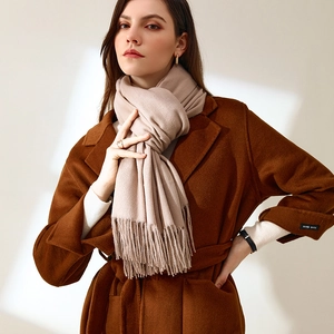 Beige faux cashmere scarf with tassels styled on a model with a brown wool coat
