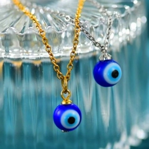 Detailed view of evil eye charms in gold and silver chains on a blue backdrop