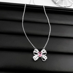 Close-up of pink zircon bow necklace with silver pendant on black textured leather
