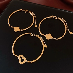 Dettaglio macro di bracciali placcati in oro 18 carati con quadrifoglio e zucca d'oro