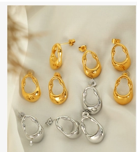 Close-up of gold and silver irregular geometric oval earrings on cream silk fabric