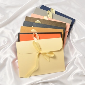 Elegant envelope gift boxes for silk scarves with matching ribbon bows on white silk