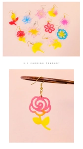 Macro shot of assorted flower and snowflake resin earring pendants on a pink background
