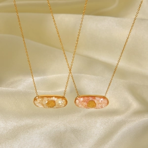 Elegant gold stainless steel necklaces with shell pendants and charms on silk fabric