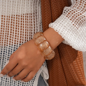 Close-up of amber acrylic cuff bracelet with gold glitter on a model's wrist
