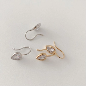 Close-up of heart-shaped crystal earrings with silver and gold hooks on textured background