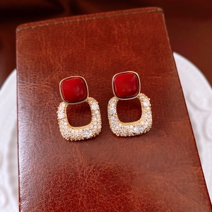 Détail de boucles d'oreilles carrées plaquées or 18 carats avec pierre rouge sur cuir
