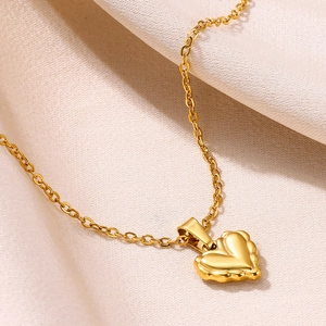 Détail du pendentif cœur plaqué or 18k avec bords festonnés sur fond de soie douce