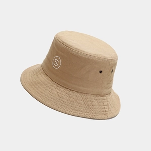 Detail of khaki bucket hat featuring white S letter embroidery and metal eyelets