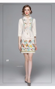 Detailed view of floral embroidery and bow tie neckline on an elegant beige dress