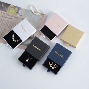 Flat lay of colorful drawer jewelry boxes with gold logo on decorative newspaper