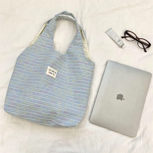 Detail shot of blue woven tote bag texture with colorful stitching and brand label