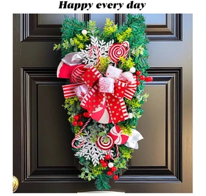 Detail of a Christmas teardrop door swag with red candy canes and festive ribbons