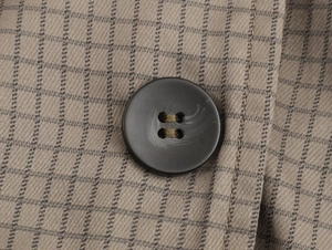 Detailed macro view of the greyish-brown checkered fabric and dark brown resin button