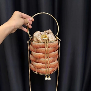 Detailed close-up of champagne rhinestone bucket bag with metal handle and pearl pendant