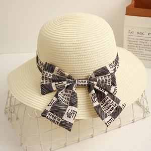Detailed weave of beige straw sun hat featuring a monochrome checkered bow with text