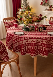 Detailed close-up of red Christmas round tablecloth with deer patterns and gold lace edge