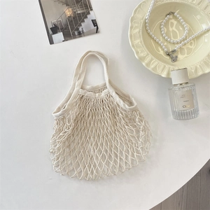 Detailed close-up of cream woven mesh beach bag with cotton rope texture and retro design
