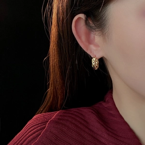 Close-up of gold plated pleated hoop earrings on model highlighting metallic texture