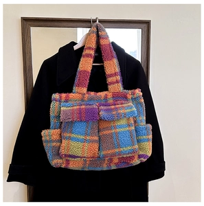 Detail of colorful plaid faux shearling tote bag with functional front pockets and soft texture