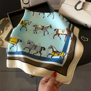 Detail eines quadratischen Seiden-Halstuchs mit Pferdeprint in Blau, Braun und Beige
