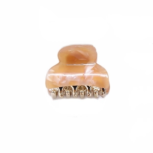 Detailed close-up of orange marble acetate hair claw with durable gold metal teeth
