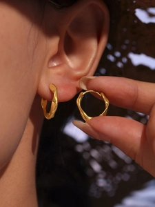 Détail macro des boucles d'oreilles créoles torsadées en acier inoxydable plaqué or 18K