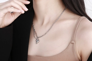 Dettaglio della collana a cuore argento con maglia cubana e graffetta sulla modella