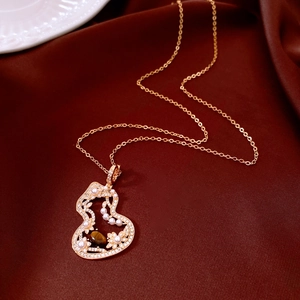 Detailed macro view of gold hollow gourd necklace with tiger eye stone and pearls