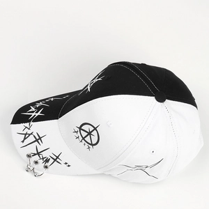 Detail of black and white baseball cap featuring silver rings and graffiti star prints