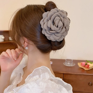 Detailed view of large grey fabric rose hair claw clip styled on a French bun hairstyle