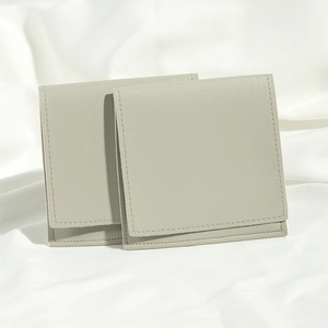 Detailed view of two grey PU leather jewelry pouches with neat stitching on white fabric