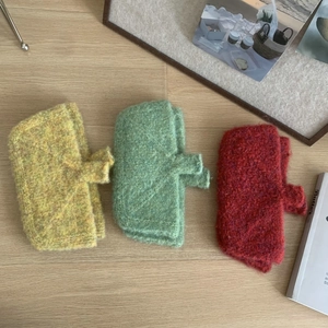 Close-up of yellow, green, and red knitted mini bags on a wooden floor