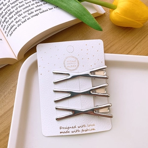 Three silver Y2K metal hair clips on a handmade card with a tulip on a wooden table