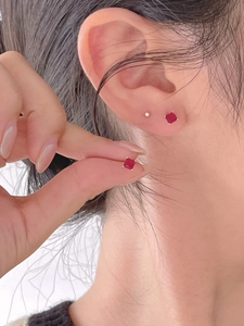 Macro shot of minimalist square red zircon stud earrings with silver claw setting