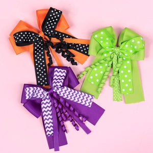 Three handmade polka dot Halloween hair bows with long ribbons on pink background