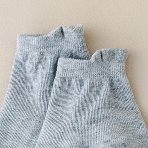 Close-up of grey knit baby socks with anti-slip grip and unique ear-shaped ribbed cuffs