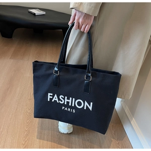 Detail der schwarzen Canvas-Einkaufstasche mit FASHION PARIS Aufdruck und Ledergriffen
