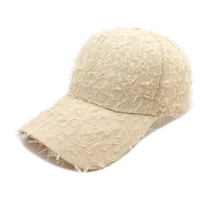 Detailed view of the distressed raw edge and fringe texture on a beige baseball cap