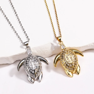 Elegant gold and silver sea turtle necklaces with sparkling zircon inlay on white marble