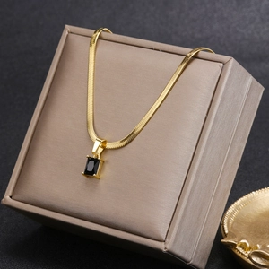 Detalle del collar de cadena dorada con un colgante de cristal negro rectangular fino